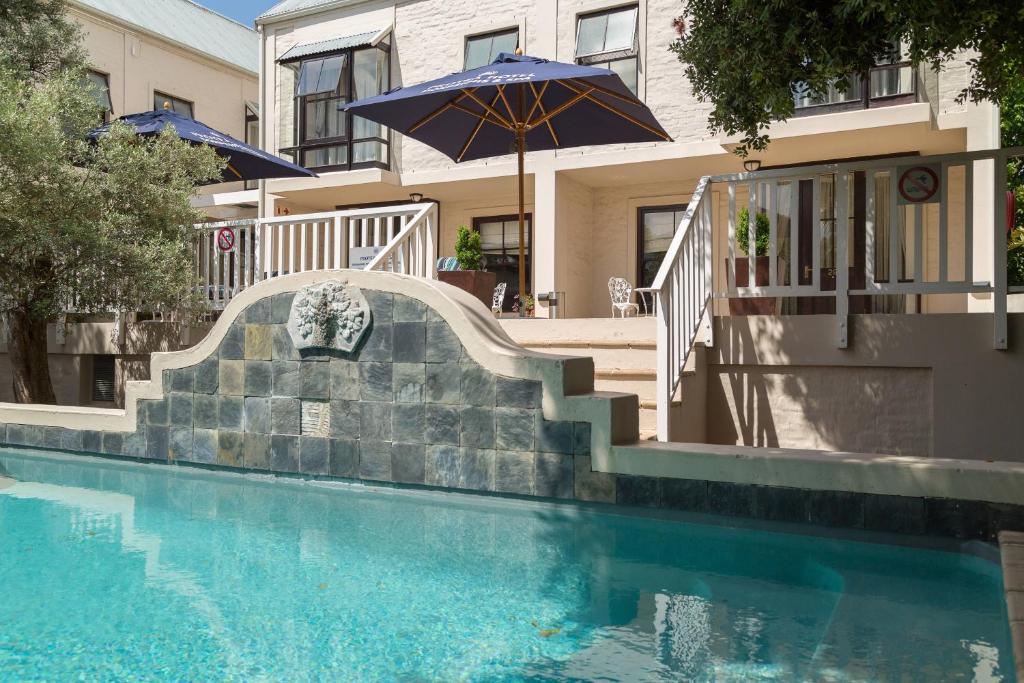 a swimming pool with a staircase and an umbrella at Protea Hotel by Marriott Dorpshuis & Spa Stellenbosch in Stellenbosch