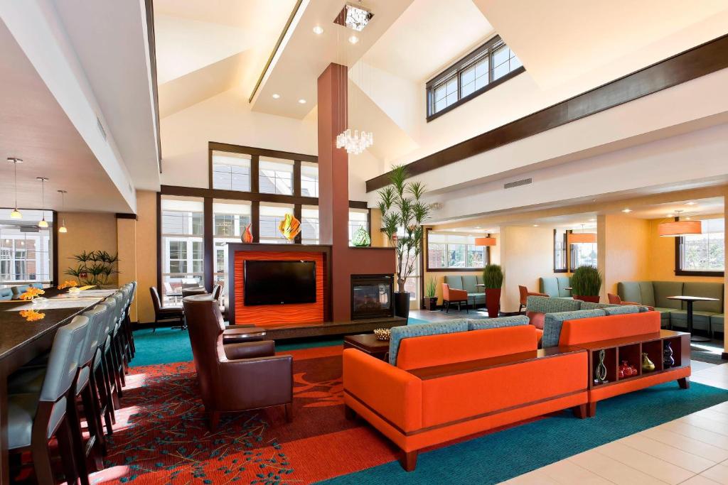 eine Lobby mit orangefarbenen Sofas und einem Kamin in der Unterkunft Residence Inn Bismarck North in Bismarck