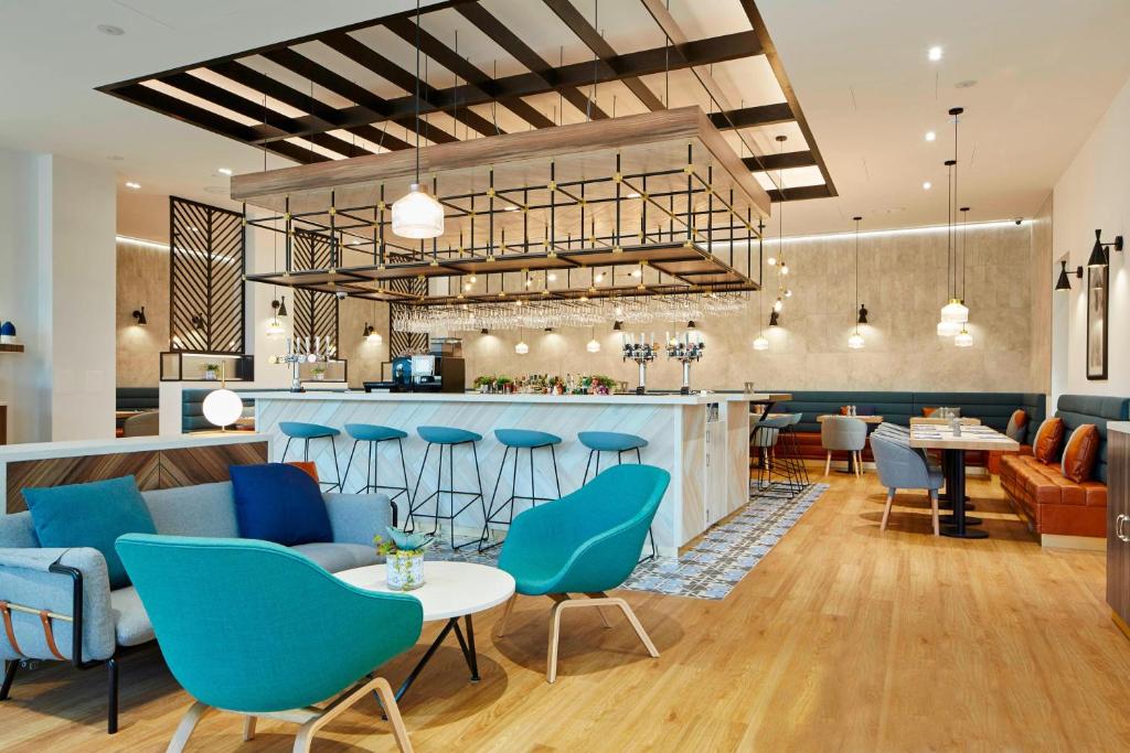 a lobby with blue chairs and a bar at Courtyard by Marriott Luton Airport in Luton