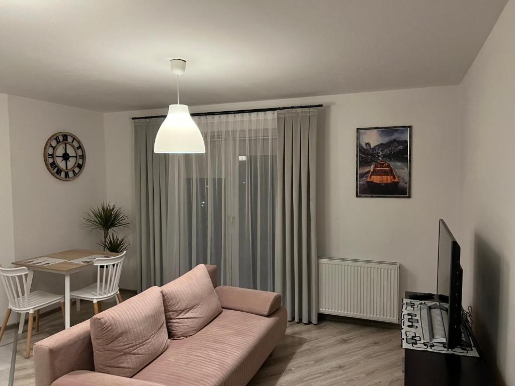 ein Wohnzimmer mit einem rosa Sofa und einem Tisch in der Unterkunft Apartament Zlota Jesień 2C in Krakau