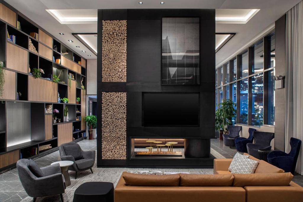 a living room with a tv and a couch and chairs at Four Points by Sheraton Flushing in Queens