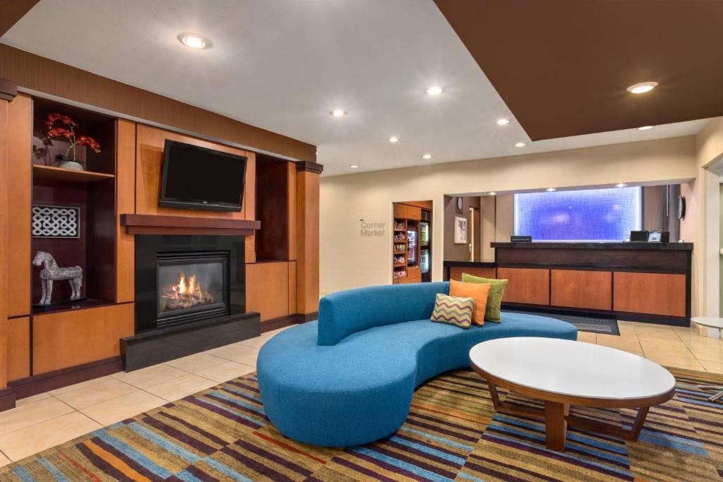 a living room with a blue couch and a fireplace at Fairfield Inn & Suites by Marriott Norman in Norman