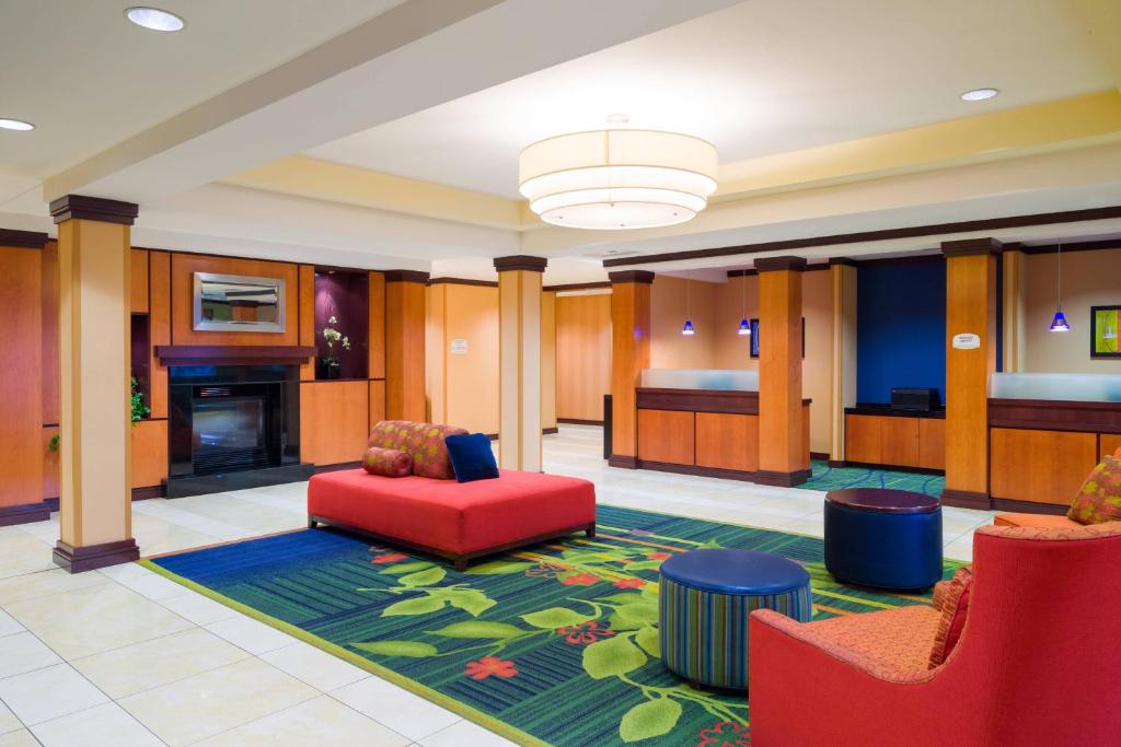 a hotel lobby with red chairs and a fireplace at Fairfield Inn & Suites Lock Haven in Lock Haven