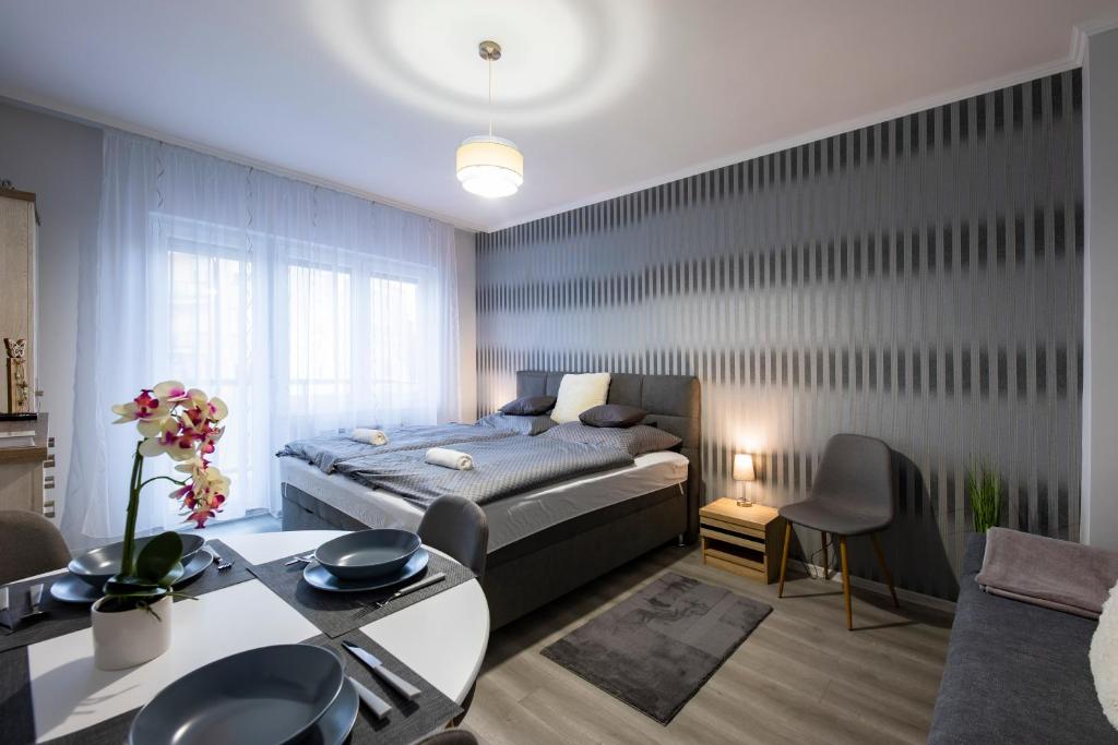 een slaapkamer met een bed en een tafel en stoelen bij Csipke Apartman in Makó