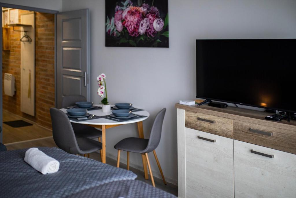 Pokój z telewizorem i stołem z krzesłami w obiekcie Csipke Apartman w mieście Makó