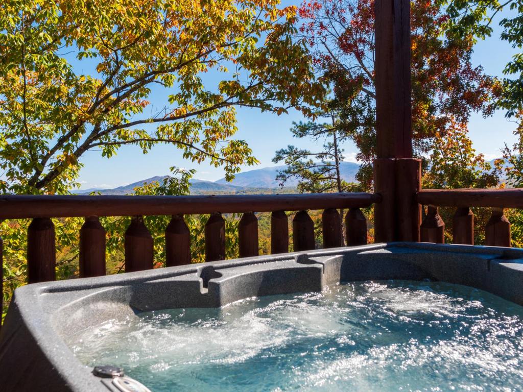 a hot tub on a deck with trees at Grand Mountain View Lodge By Ghosal Luxury Lodging in Sevierville