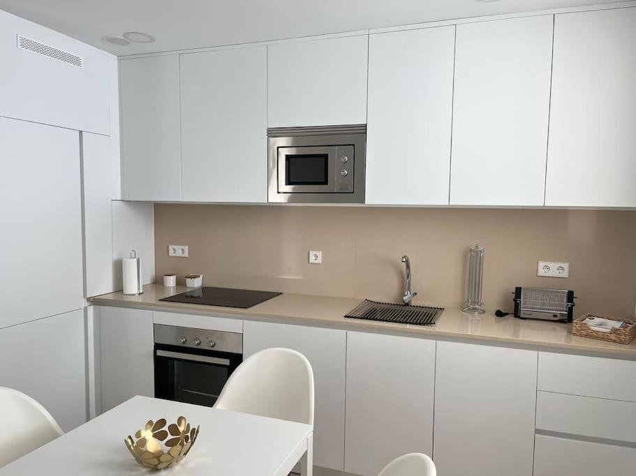 a kitchen with white cabinets and a table with chairs at IDEAL ESTUDIO PARA PAREJAS in Conil de la Frontera