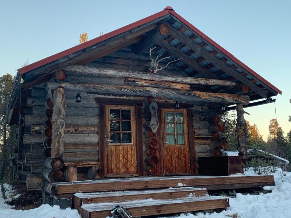ein Blockhaus mit einer Veranda im Schnee in der Unterkunft Log Cabin - Lord of Sormuset in Inari