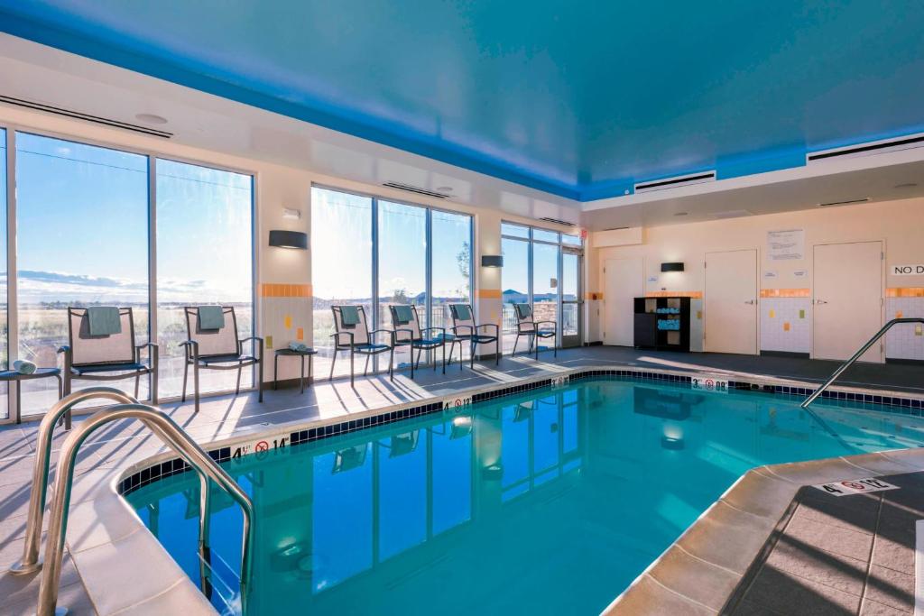 een zwembad met stoelen, tafels en ramen bij Fairfield Inn & Suites by Marriott Moses Lake in Moses Lake