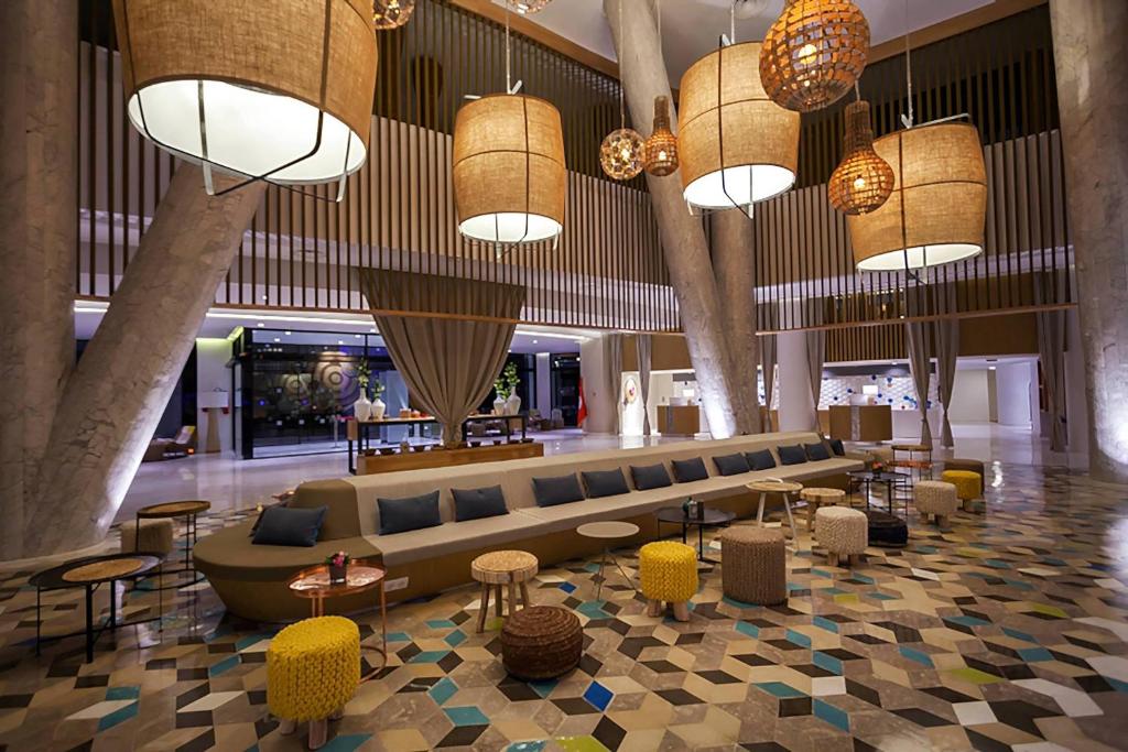 eine Lobby mit einem Sofa, Tischen und Kronleuchtern in der Unterkunft Sousse Pearl Marriott Resort & Spa in Sousse