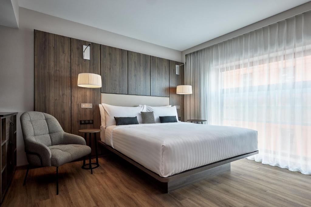 a bedroom with a bed and a chair and a window at AC Hotel by Marriott Strasbourg in Strasbourg