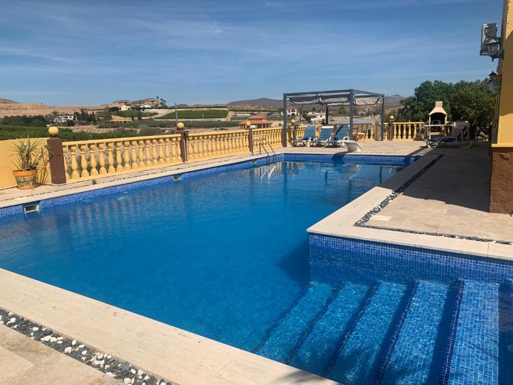 a large swimming pool with a fence and blue water at Private villa large pool elevated quiet secluded location, near Mojacar in Antas
