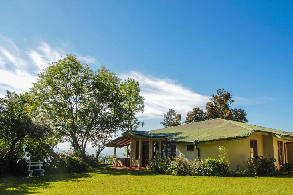 a yellow house with a green roof on a grass field at Hatale Mini World's End Bungalow in Madulkele