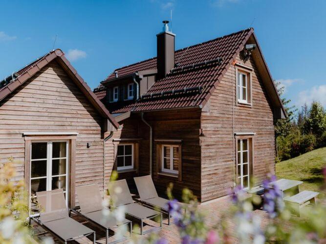 Casa de madera con 2 sillas y patio en Holiday homes in Torfhaus Harzresort, Torfhaus, en Torfhaus