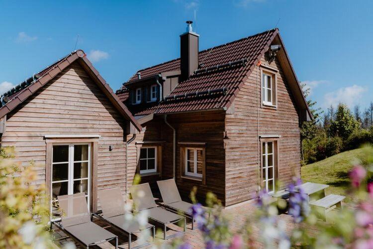 a wooden house with benches in front of it at Ferienhäuser im Torfhaus Harzresort, Torfhaus in Torfhaus