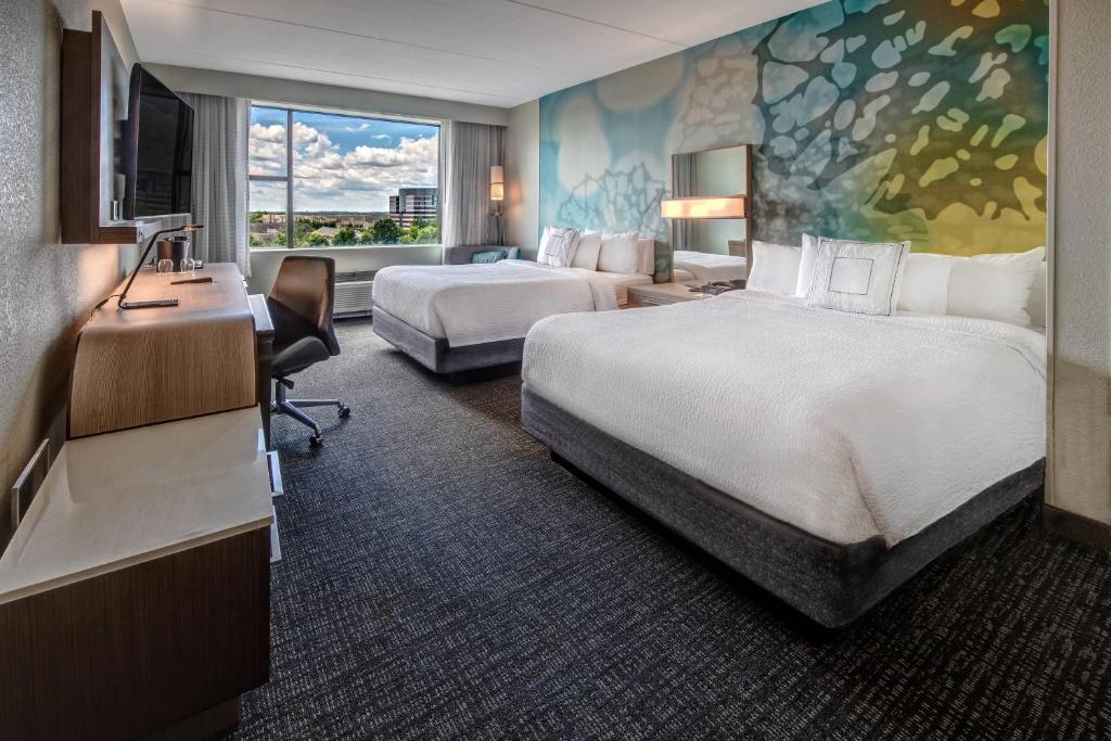 a hotel room with two beds and a desk at Courtyard by Marriott Dulles Airport Herndon in Herndon