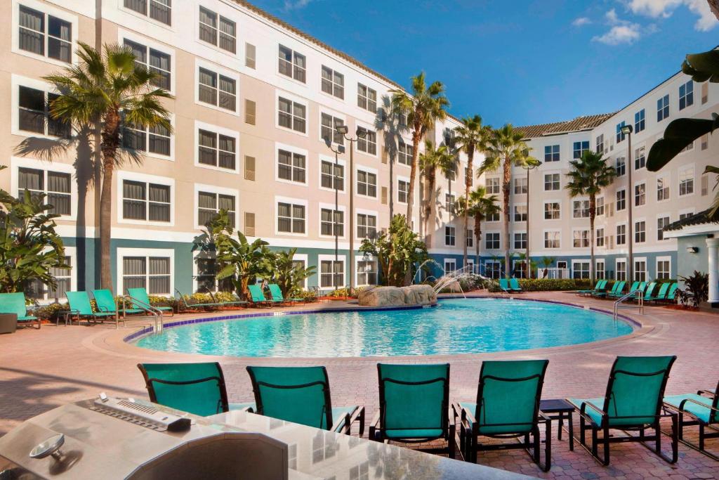 a pool at a hotel with chairs and a building at Residence Inn Orlando Lake Buena Vista in Orlando