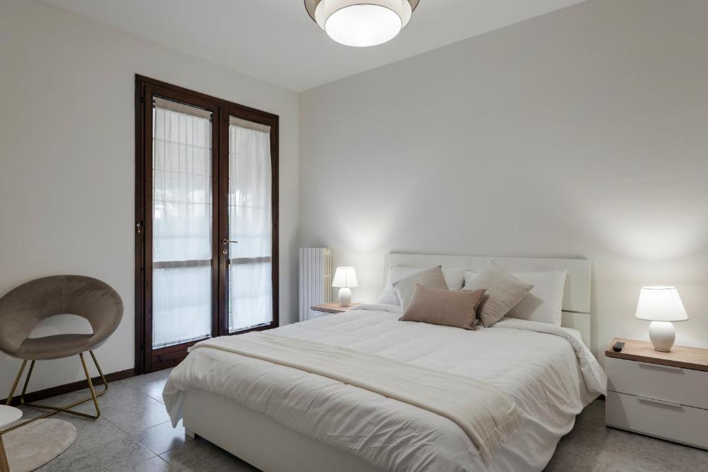 - une chambre blanche avec un grand lit et une chaise dans l'établissement La Maison, à Peschiera del Garda