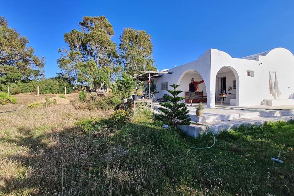 Ein weißes Haus auf einem Feld mit einem Hof in der Unterkunft Maison de vacance pour les amateurs de la nature in Kelibia