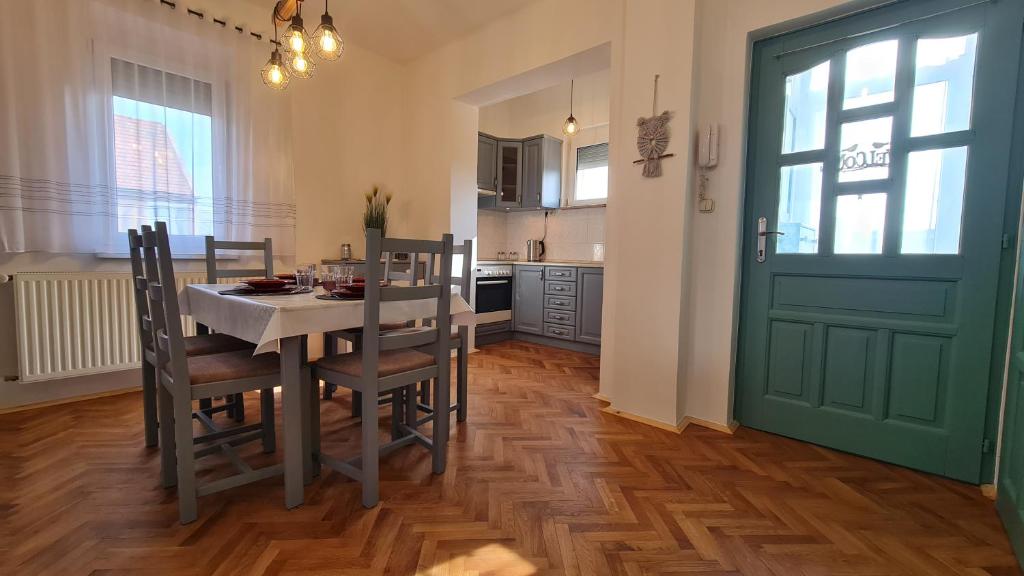 una cocina con mesa y sillas y una puerta verde en RI-JÓ apartman, en Mohács