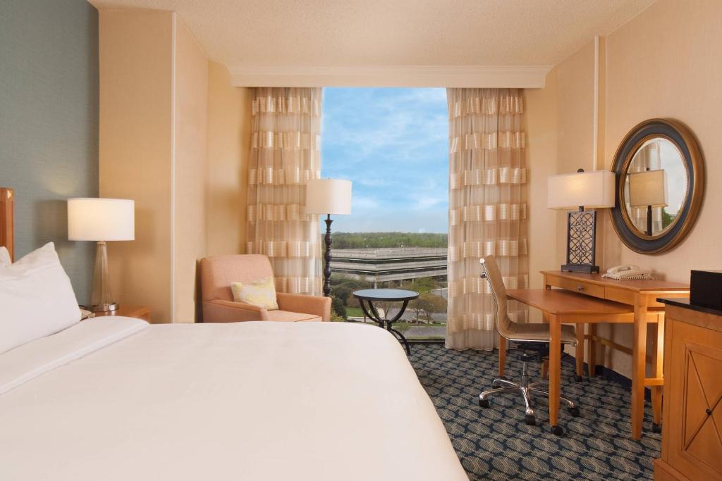 グリーンビルにあるGreenville Marriottのベッド、デスク、窓が備わるホテルルームです。