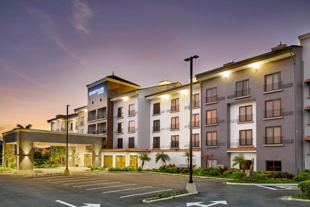 a large white building with a parking lot at Courtyard by Marriott San Jose Escazu in San José