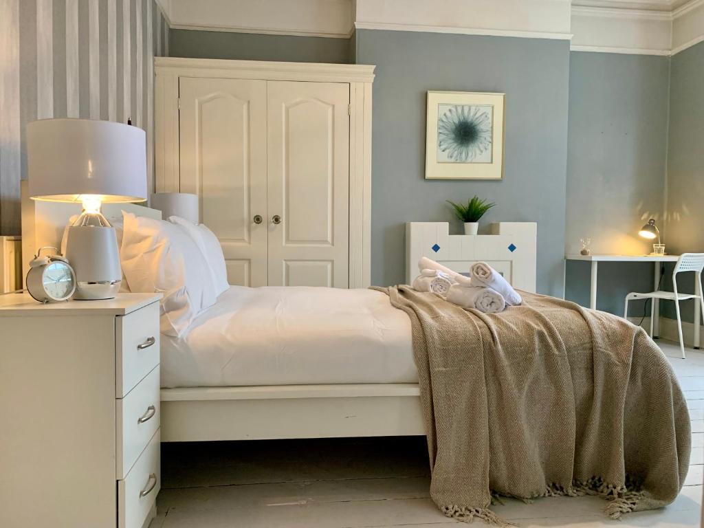 Un dormitorio con una cama blanca con una manta. en Somerford Place - 6 Beds - Sleeps 12 - Parks 2-3 cars/vans, en Willenhall