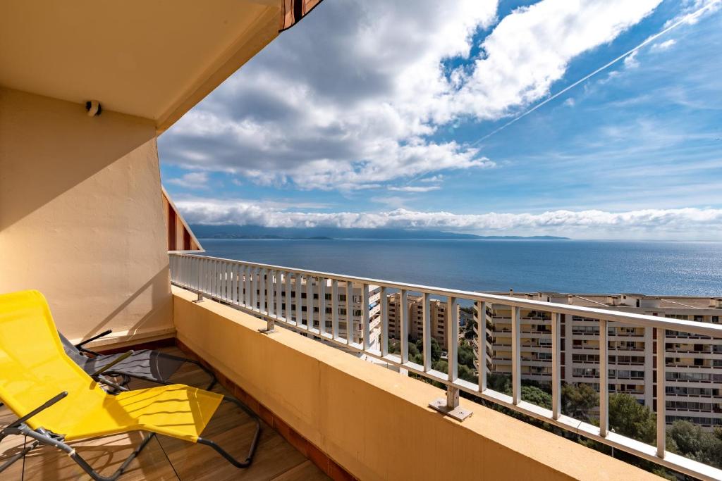 d'un balcon avec une chaise jaune et une vue sur l'océan. dans l'établissement Helios, Sanguinaires, vue mer magnifique, T2 4pers, à Ajaccio