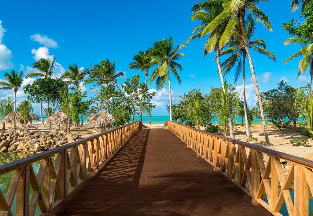 eine Holzbrücke über einen Strand mit Palmen in der Unterkunft Temptation Miches Resort, Punta Cana - All Inclusive - Adults Only in Punta Cana