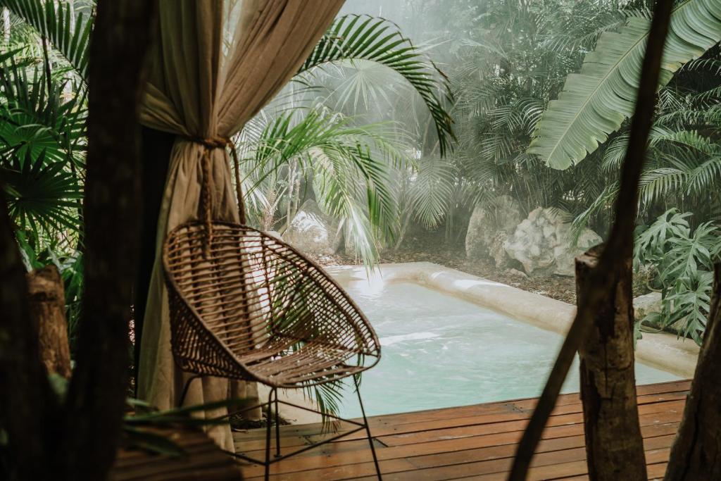 a chair sitting on a deck next to a swimming pool at Copal Tulum Hotel in Tulum