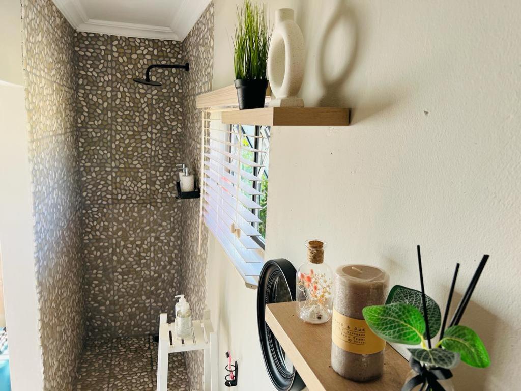 a bathroom with a desk with plants and a shower at Bird Nest Lodge in Durban