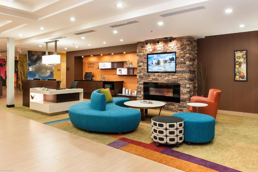 a living room with a fireplace and blue chairs at Fairfield Inn & Suites by Marriott Vernon in Vernon