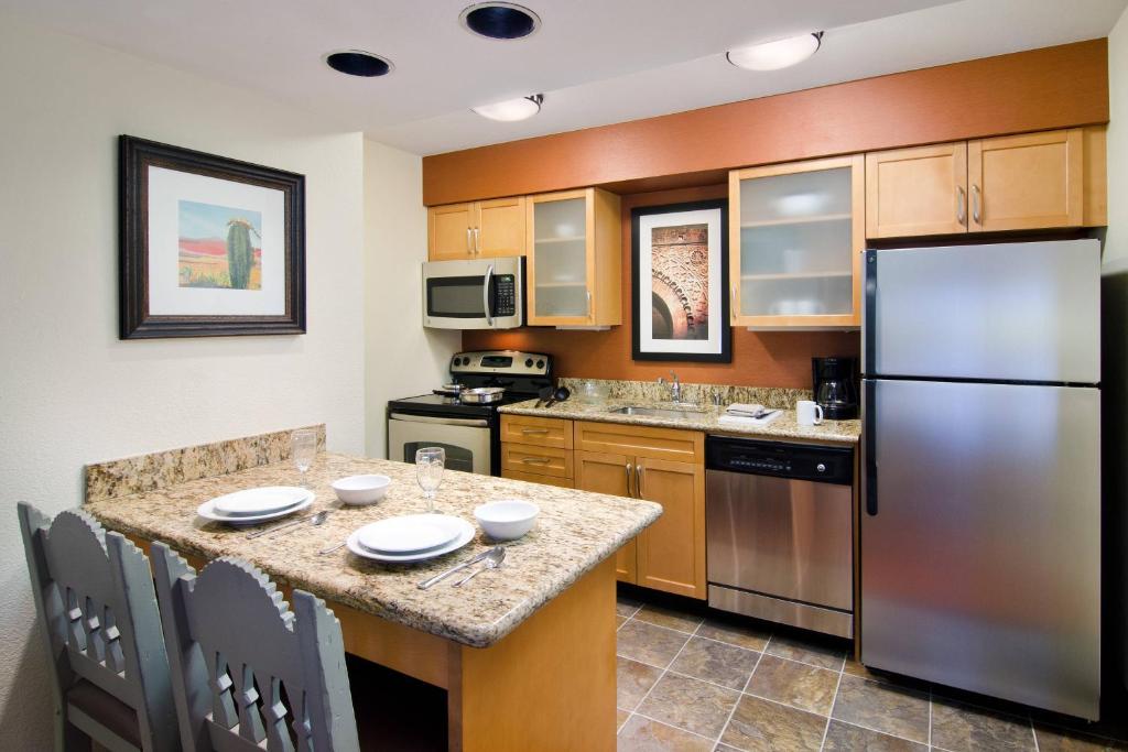 eine Küche mit einem Kühlschrank und einem Tisch mit Stühlen in der Unterkunft Residence Inn Santa Fe in Santa Fe