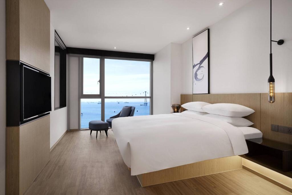 - une chambre avec un grand lit blanc et une grande fenêtre dans l'établissement Fairfield by Marriott Busan Songdo Beach, à Busan