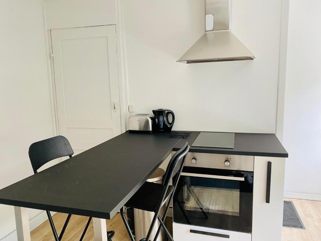 une cuisine avec un comptoir noir et des chaises dans l&#39;établissement Maisonette Tran, à Lille