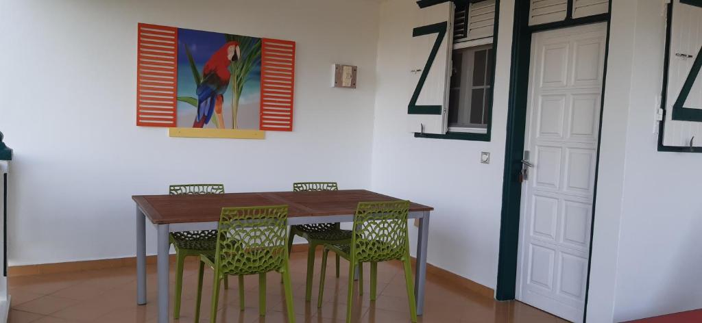 Grand-Bourg的住宿－Résidence KAYA, Marie-Galante，餐桌、椅子和墙上的绘画