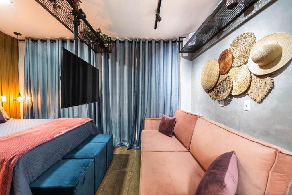 a bedroom with a couch and a bed with hats on the wall at Kaza Noah Sky Pauliceia in Sao Paulo