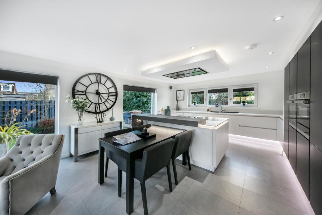 a kitchen with a table and a clock on the wall at Countesswells Crescent Villa ✪ Grampian Lettings Ltd in Aberdeen