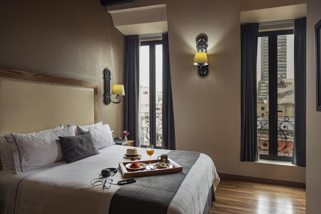 a hotel room with a bed with a tray of food on it at Historico Central Hotel in Mexico City