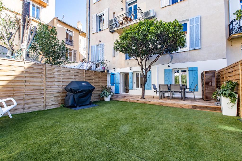 een achtertuin met een gazon en een hek bij A Quiet Place with Garden in the heart of Cannes in Cannes