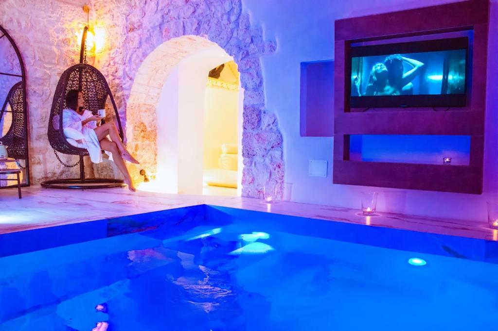 a swimming pool with a tv in a room at Dimora Farina Suites in Ostuni