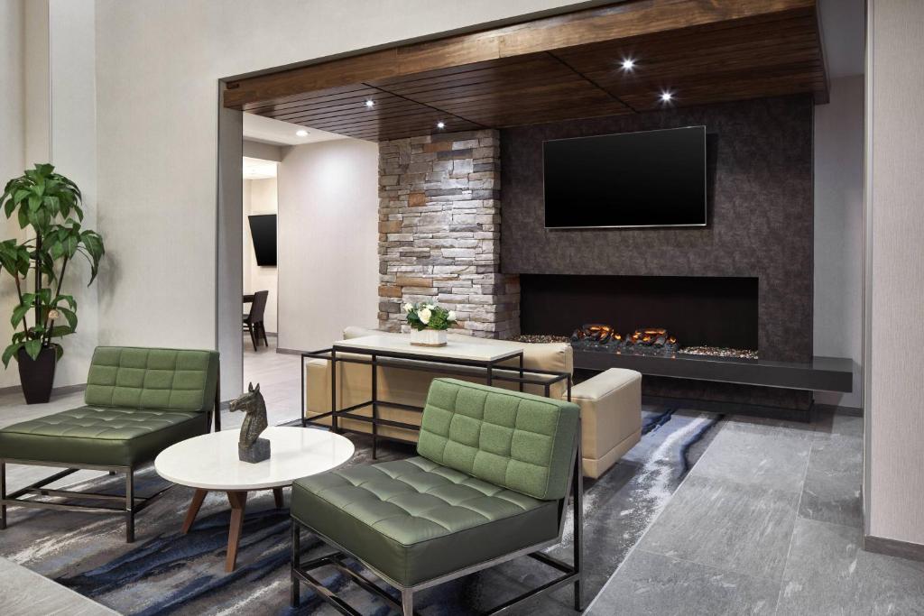 a lobby with a fireplace and green chairs at Fairfield Inn & Suites by Marriott Virginia Beach/Norfolk Airport in Virginia Beach