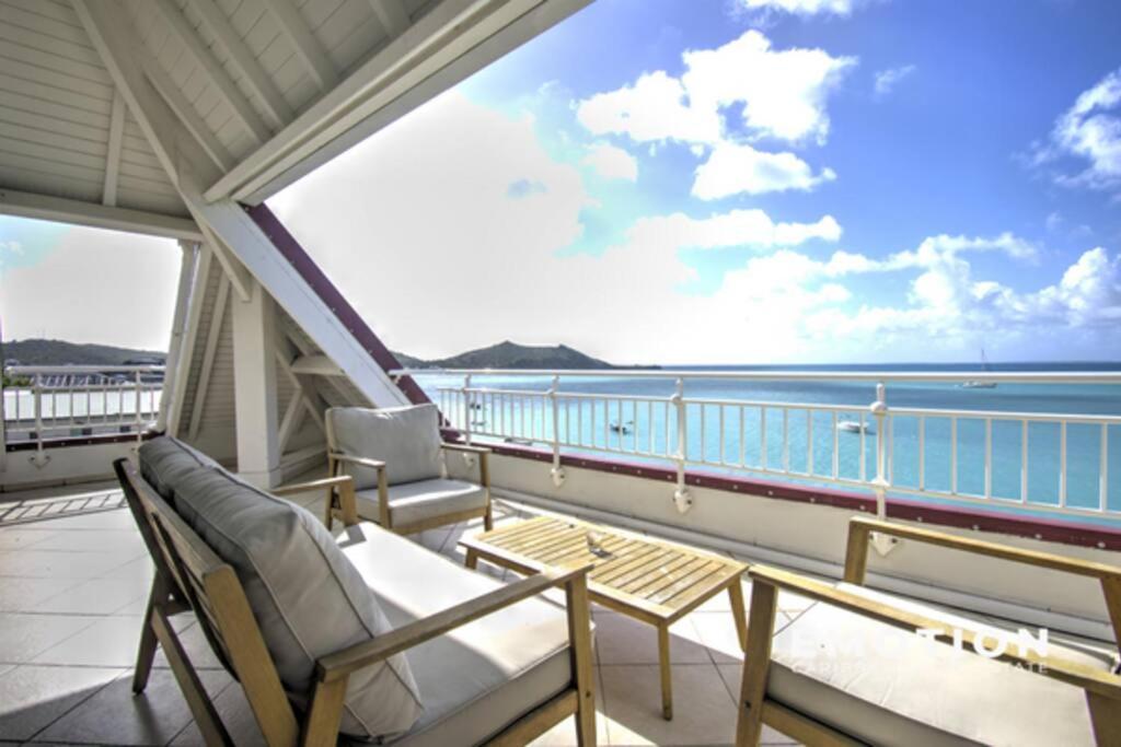 Un balcón con sillas y vistas al océano. en Deux pièces sur la belle plage de Grand Case, en Grand Case