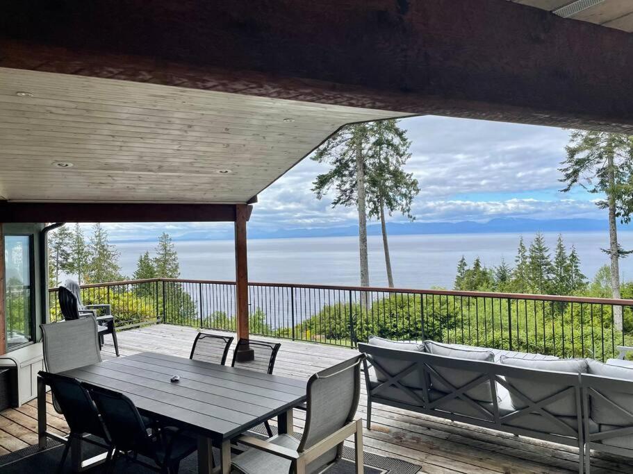 einen Holztisch und Stühle auf einer Terrasse mit Aussicht in der Unterkunft Barooga: Stunning View Home in Halfmoon Bay, Canada in Halfmoon Bay