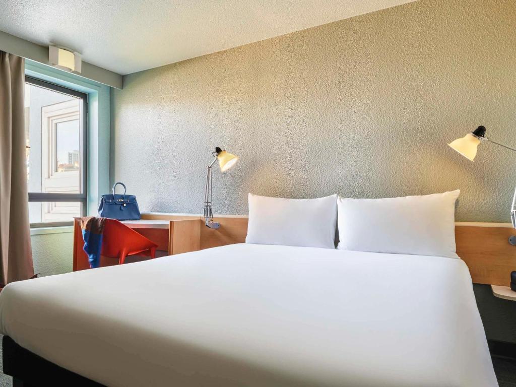 - une chambre avec un grand lit blanc et un bureau dans l'établissement ibis Paris La Villette Cité des Sciences 19ème, à Paris