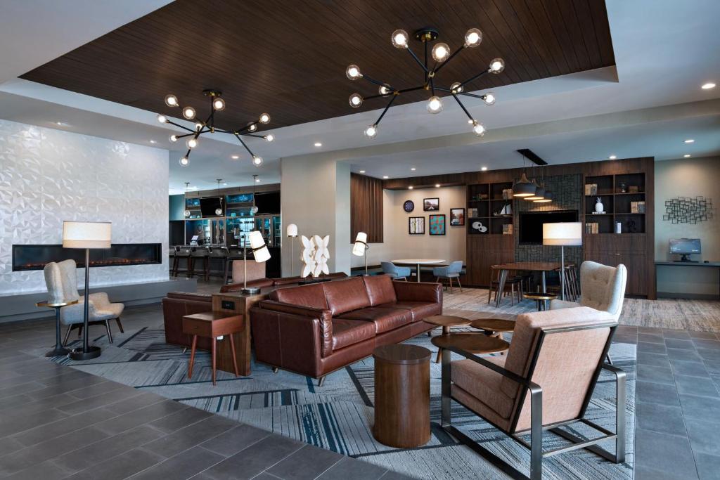 a lobby with a leather couch and chairs and tables at Four Points by Sheraton Fort Worth North in Fort Worth