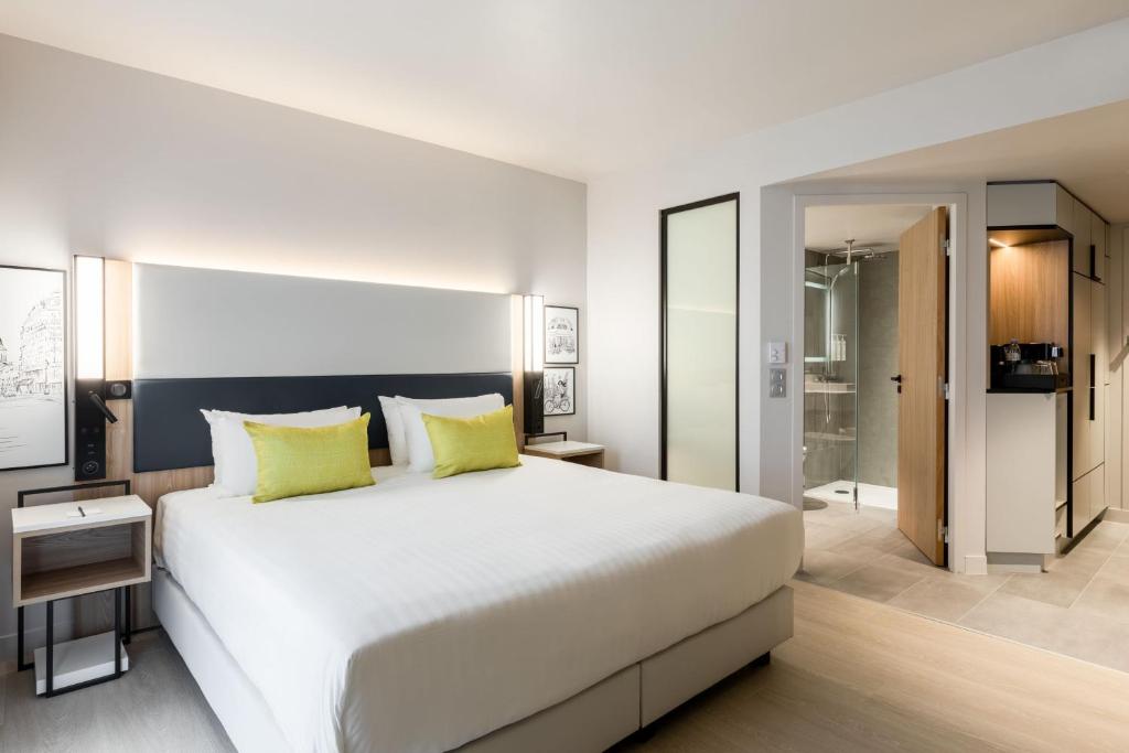 Un dormitorio con una gran cama blanca con almohadas amarillas. en Courtyard by Marriott Paris Creteil, en Créteil