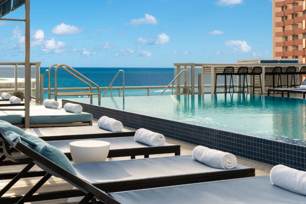 a swimming pool with chaise lounge chairs and the ocean at AC Hotel by Marriott Miami Beach in Miami Beach