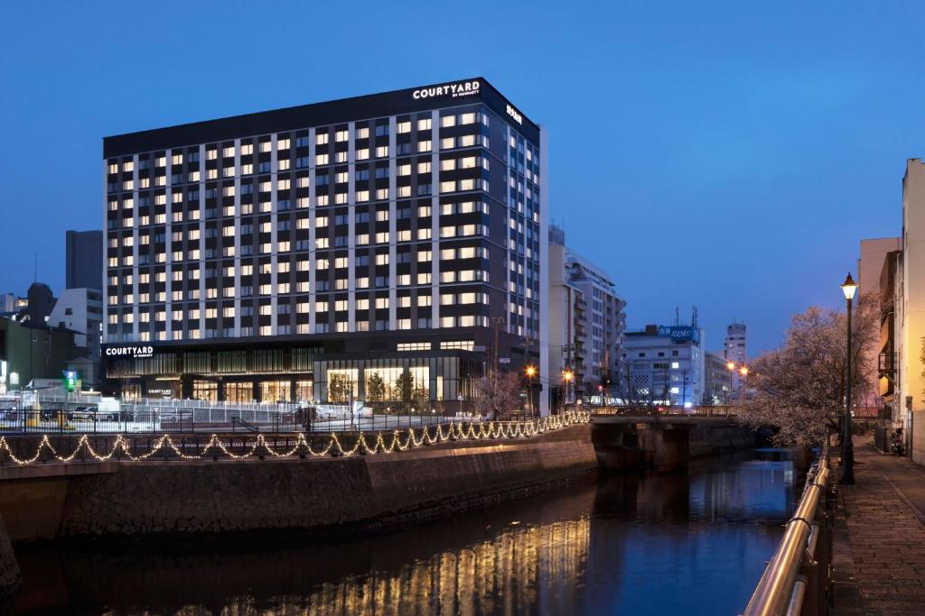 a tall building next to a river in a city at Courtyard by Marriott Nagoya in Nagoya