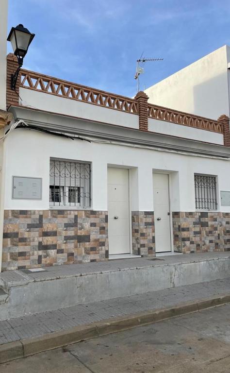 a white building with four doors and a roof at La casita de la punta in Isla del Moral